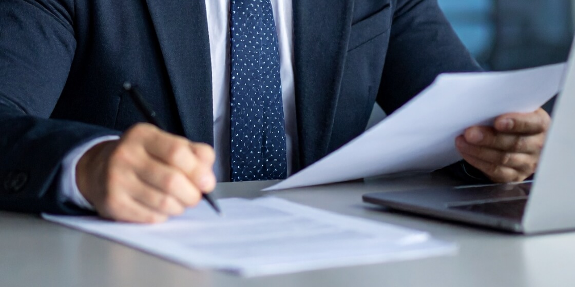 書類に記入するスーツの男性の手元の画像